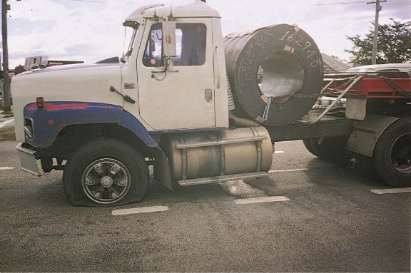 Side view of a prime mover with a rolled steel coil on the chassis and a flat tyre