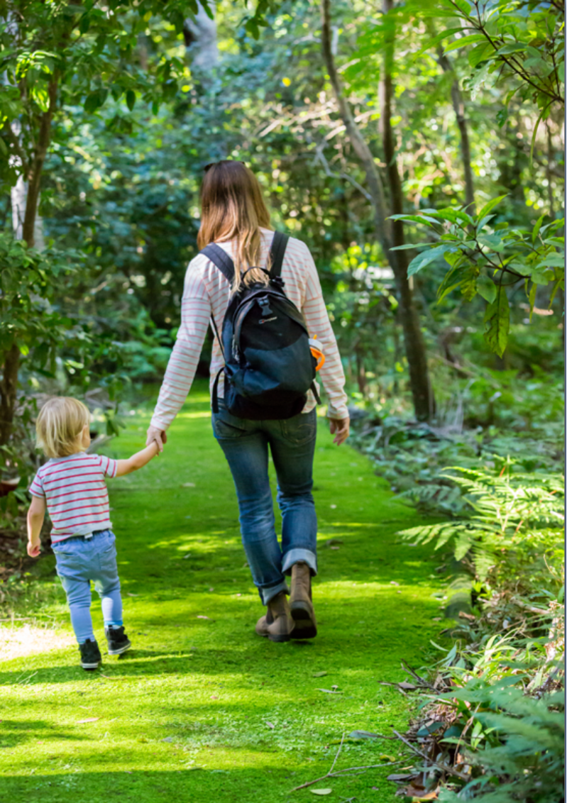 Photograph of a young mother and young child walking hand in hand along a track in Booderee Botanic Gardens
