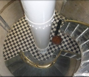 view looking down from top floor to bottom floor, with pedestal, staircase and chequered floor 