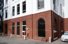 Corner of a brick building with an arched window and three rectangular windows visible.