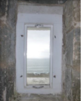 Photograph showing framed rectangular window set into stone walls.