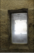 Photograph showing rectangular window set into stone walls.