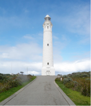 Photograph showing tall white lighthouse tower with lantern house against blue sky.