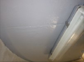 Photograph showing grey underside of lantern room floor. A modern light fixture is fitted to surface. 