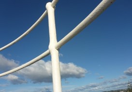 Photograph showing close up of white iron pipe railing. 