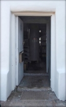 Photograph showing entry door standing ajar to reveal small lighthouse entrance room. 