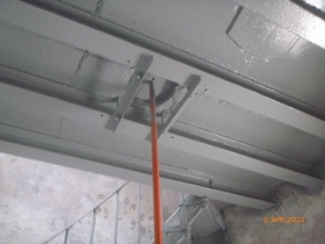 Photograph showing underside of a curved half-floor supported by beams.