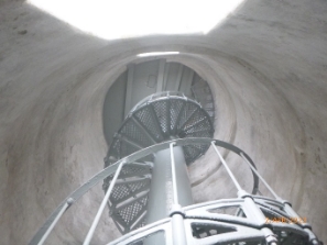 Photograph showing underside of spiral staircase ascending to floor above. 