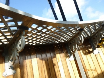 Photograph of curved lattice catwalk fitted to ornate brackets attached to internal wooden lantern room walls.