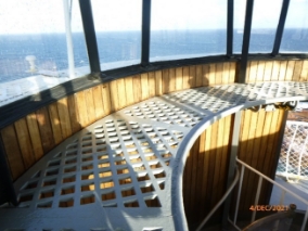 Photograph of curved lattice catwalk fitted inside lantern room, fixed below glazing panes.