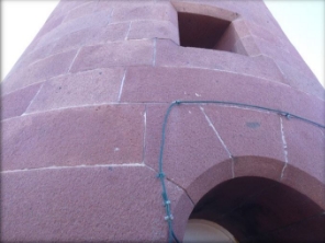 Photograph of granite entrance archway at base of lighthouse tower. A small window is set into the stone above the archway.