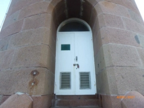 Photograph of double doors set into granite lighthouse tower with arched top.
