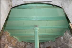 Photograph of the underside of a round floor, supported by beams and a central column.