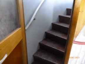 Photograph of small staircase corridor leading to room through door.