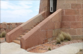 Photograph of granite stairs leading from base of lighthouse tower to doorway.