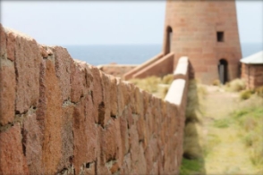 Photograph of granite windbreak wall running to base of granite lighthouse.