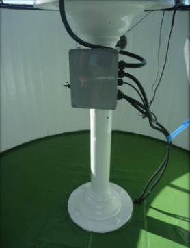 Photograph showing painted cast iron pedestal fitted to centre of circular lantern room floor. An electrical box with cables is attached to the side of the pedestal.