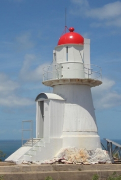 Photograph showing small white lighthouse with red dome roof and small arched porch room.