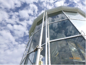 Photograph showing glazed lantern room of lighthouse tower. Large prismatic lens can be seen sitting inside the lantern room. 