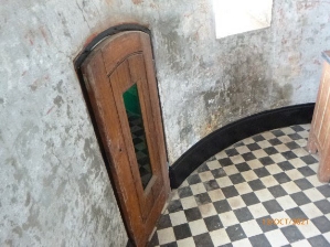 Photograph showing small arched wooden door fitted to concrete walls.