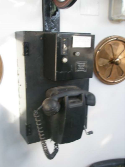 Photograph showing black telephone mounted to box inside lighthouse lantern room.
