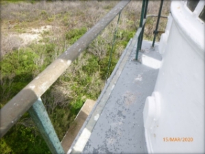 Photograph showing small grey balcony floor with curved white lantern house standing beside bare balcony balustrades.