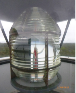 Photograph showing prismatic lens sitting on circular pedestal inside a lantern house.