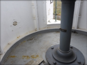 Photograph showing circular lantern room floor with grey pedestal fixed to centre.