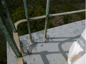 Photograph showing non-ferrous metal bar rails and stanchions bolted to small grey balcony floor.