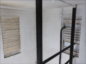 Photograph showing internal walls of lighthouse tower with two windows with painted glass louvres.