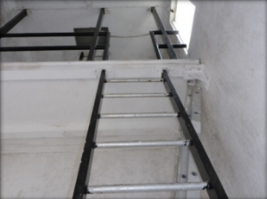 Photograph showing fixed ladder leading to mezzanine level above.