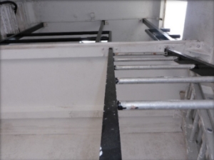 Photograph showing fixed ladder leading to mezzanine level above.