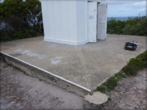 Photograph showing square concrete slab with white lighthouse tower sitting in centre. 