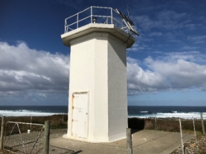 Photograph showing white lighthouse tower with a flat balcony and no lantern house.
