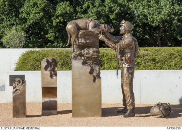 Brass sculpture of a dog elevated on a platform and an australian soilder looking the dog in the eyes.
