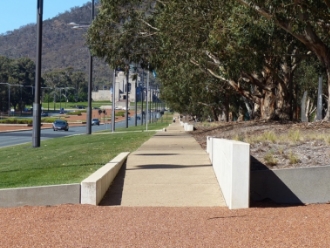 View along the eastern side of Anzac Parade with the eucalyptus under planted with native grasses, the pedestrian pathway, irrigated grass, streetlights and road beyond