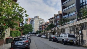 A picture showing residential buildings and parked cars along Kirribilli Avenue. 