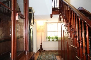 A close up picture of the stair hallway showing details of the wooden staircase and surrounding furniture. 