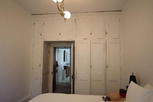 A picture of bedroom 2 at Kirribilli House with white walls, closets, framing and bedsheets.