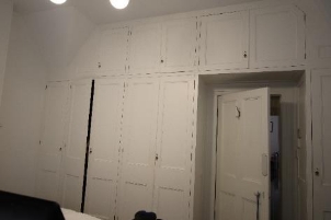 A picture of bedroom 3 at Kirribilli House showing white walls, closets, and door.