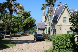 A picture of the Kirribilli House entry gate and driveway with a car on the gravel driveway in front of the property.