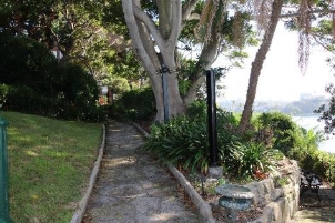 A picture of a stone pathway with stone walls, grass and trees to its sides. 