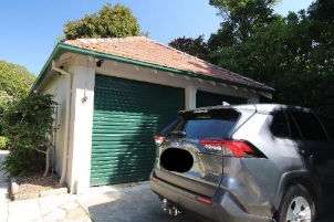 A picture of a garage with a green roller door and orange brick roof at Kirribilli House