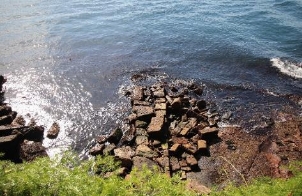 A picture of large scattered rocks at the Kirribilli House boat harbour with waves of water surrounding the area