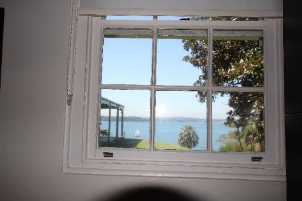 A picture of the Kirribilli House staff window with white walls and framing surrounding the view of outside the window. 