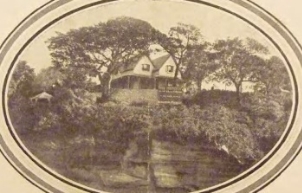 A sepia tone picture of Kirribilli House from the harbour, surrounded by large trees and on top of large rocks 