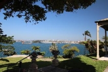 A picture of the harbour view from Kirribilli House grounds surrounded by grass, trees and the harbours water and Sydney CBD in the distance