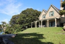 A picture of Kirribilli House from the back depicting the property being perched up on a green grass slope. 