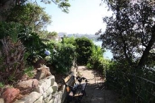 A picture of a path and stone wall surrounded by trees and bushes at Kirribilli House 