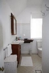 A picture of a bathroom in Kirribilli House with white fittings, walls and towels and dark wood stained cabinet and mirror frame